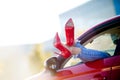 Photo of woman`s legs in red shoes sticking out of red car window Royalty Free Stock Photo