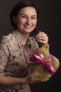 Photo woman with straight dark hair, posing in a shirt with painted flowers on dark background in Studio