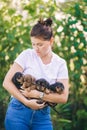 Photo of woman in white T-shirt holding four puppies outdoors