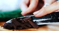 Photo of a woman who is cutting chocolate curls with a knife