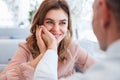 Photo of woman in love looking on her man and taking pleasure when holding male hand at her face, while having date in restaurant