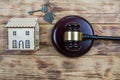 Photo with wooden house, keys and judge`s gavel on wooden background as symbol of mortgage or dilapidated housing being sold at