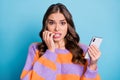 Photo of worried charming woman scared hold phone mistake post isolated on pastel blue color background