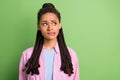 Photo of worried lady think bite lip look empty space wear striped pink shirt isolated green color background