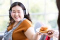 Photo of write hand holding a white plate of hamburger with soft focus on smiling fat woman with headphones use the left hand to Royalty Free Stock Photo