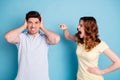 Photo of yelling wife scolding negative expression husband hiding ears wear casual t-shirts isolated blue background