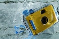 Photo of yellow waterproof camera in water with splash.