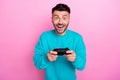 Photo of young addicted console gamer man student wear blue sweatshirt hold gamepad interested action isolated on pink