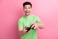 Photo of young addicted gamer brunet hair guy playing video game using wireless connection gamepad isolated on pink