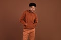 Photo of young african handsome guy hands in pocket wear sweatshirt serious isolated over brown color background Royalty Free Stock Photo