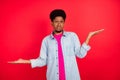 Photo of young afro guy weighing measure pros cons solution decision advertise isolated over red color background Royalty Free Stock Photo