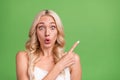 Photo of young amazed crazy girl stare haze point finger copyspace advertise product isolated on green color background