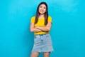 Photo of young asian beauty girl hold crossed arms toothy smile wear denim skirt yellow t-shirt isolated blue color Royalty Free Stock Photo