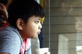 Young Asian boy drink from a paper cup inside a fast food restaurant