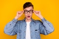 Photo of young astonished man hands touch eyeglasses ophthalmology healthcare isolated over yellow color background