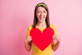 Photo of young attractive cheerful smiling good mood girl wink eye hold big red heart isolated on pink color background
