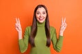 Photo of young attractive smiling excited happy girl showing v-sign wear green turtleneck isolated on orange color