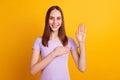 Photo of young attractive woman hand on chest make promise swear isolated over yellow color background