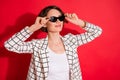 Photo of young attractive woman happy positive smile look empty space hands touch sunglasses isolated over red color Royalty Free Stock Photo