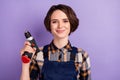 Photo of young attractive woman happy smile builder repairer hold perfarator tools isolated over violet color background Royalty Free Stock Photo