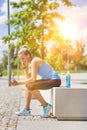 Portrait of young attractive woman sitting while using and listening to music on her smartphone in park Royalty Free Stock Photo