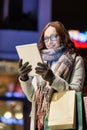 Portrait of young attractive woman smiling and using digital tablet while on night shopping Royalty Free Stock Photo