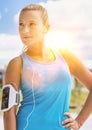 Portrait of young attractive woman standing while listening to music on her smartphone in park Royalty Free Stock Photo