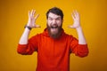 Young bearded angry man is screaming at the camera on yellow background.