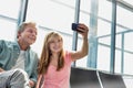 Portrait of young beautiful teenage girl taking selfie with her father in airport Royalty Free Stock Photo