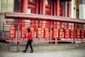 Photo of young beautiful woman turning red prayer wheels in buddhist temple.