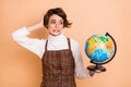 Photo of young beautiful worried anxious girl in glasses hold globe have problems in geography isolated on beige color
