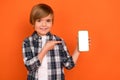 Photo of young boy indicate finger mobile electronic panel menu app download recommend isolated over orange color