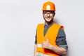 Photo of young building constructer. Wearing orange hard hat, showing thumb up