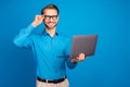 Photo of young business man happy positive smile hand touch glasses use laptop isolated over blue color background Royalty Free Stock Photo