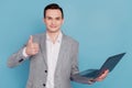 Photo of young business man happy positive smile show thumb-up like recommend laptop isolated over blue color background Royalty Free Stock Photo