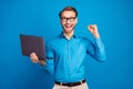 Photo of young business man happy positive smile use laptop rejoice victory fists hand isolated over blue color Royalty Free Stock Photo