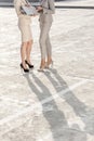 Low section of young businesswomen with laptop standing on street