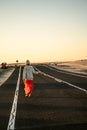 Photo of young carefree female traveler walking on the road, waiting for hitchhiking . Travel concept. Wanderlust Royalty Free Stock Photo