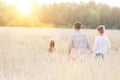 Young Caucasian family walking across field with young girl holding bouquet of flowers, concept organic ecologically friendly fami