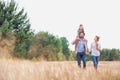 Young Caucasian family walking across field with young child on her fathers shoulders with the wife holding a bouquet of flowers