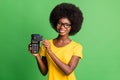Photo of young cheerful beautiful afro girl using credit card on terminal cashless payment isolated on green color