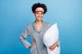 Photo of young cheerful black girl hold pillow party sleepover bedroom isolated over blue color background