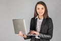 Photo of a young cheerful business woman standing over a gray wall with a laptop Royalty Free Stock Photo