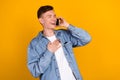Photo of young cheerful guy talk listen communication cellphone laugh joke isolated over yellow color background