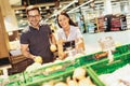 Young cheerful loving couple in supermarket with shopping trolley choosing fruits Royalty Free Stock Photo