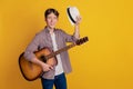 Photo of young cheerful man concert play guitar headwear performance yellow color background