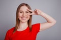 Photo of young cheerful pretty girl show fingers peace cool v-symbol isolated over grey color background Royalty Free Stock Photo