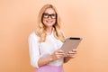 Photo of young cheerful woman blonde hair attractive model using tablet for checking applicants list isolated on beige Royalty Free Stock Photo