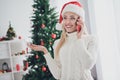 Photo of young cheerful woman happy positive smile speak talk cellphone wear santa cap noel winter indoors