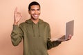 Photo of young creative web designer guy student stylish khaki jumper show okey sign recommend remote job netbook